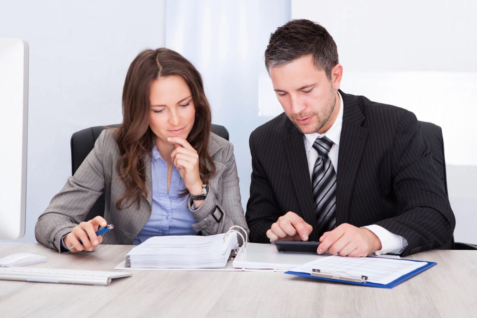 Two people sitting at a table looking at papers.